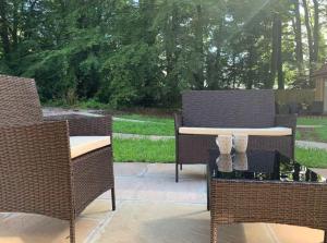 a patio with two wicker chairs and a table at Maple Lodge Cottage in Blagdon +3 photos