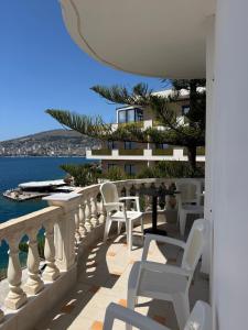 a balcony with white chairs and a view of the water at Apartments Romario in Sarandë