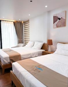 a hotel room with two beds and a window at La Mer Cat Ba Boutique Hotel in Cat Ba