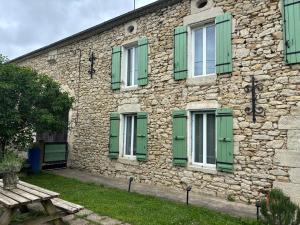 a stone building with green shutters and a wooden bench at Villabellevue in Roquebrune