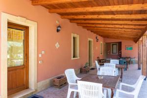 a porch with white chairs and a wooden ceiling at Lemalu con giardino in Menfi