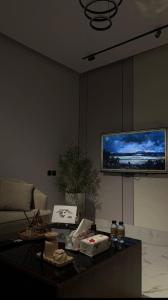 a living room with a table and a tv on the wall at شقة فندقية غرفة نوم وصالة in Hail +4 photos
