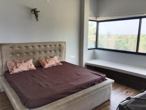a bedroom with a bed with pink pillows and a window at Raghav Sarkar Parisar in Indore