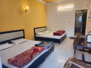 a room with two beds and a table and a mirror at Hotel Omkaar & Restaurant Chinyalisaur in Chhām