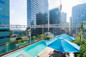 a pool with two blue umbrellas on top of a building at The Solith Hotel Managed By Nicecy in Ho Chi Minh City