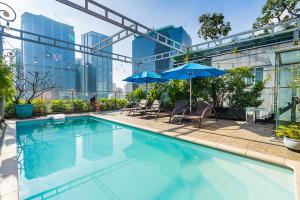 a swimming pool with chairs and umbrellas on a building at The Solith Hotel Managed By Nicecy in Ho Chi Minh City
