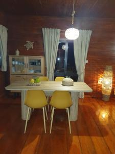 a dining room table with two yellow chairs and a light fixture at Casa do Príncipe in Santo António