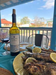 a table with a bottle of wine and a plate of fish at Casa Sheila in Mahmudia +43 photos