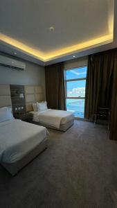 a hotel room with two beds and a large window at قلب الشمال للشقق الفندقيه in Hail