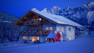 a house in the snow with mountains in the background at Appartement Sonnengarten in Ramsau am Dachstein