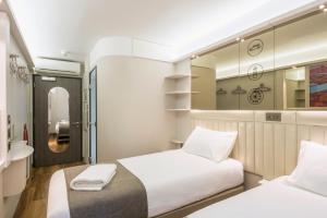 a bedroom with two beds and a mirror at Point A Hotel London Shoreditch in London