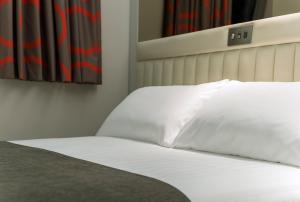 a bed with white sheets and pillows in a room at Point A Hotel London Shoreditch in London
