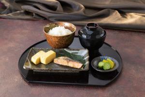 a black plate with sushi and rice on a table at ホテル ダブルイン茨木 in Ibaraki