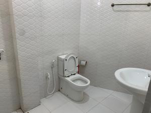 a white bathroom with a toilet and a sink at Grace Inn in Kalkudah