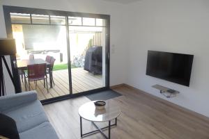 a living room with a couch and a flat screen tv at Escapade Bassin - Spa Privé - Maison 6 Pers in Audenge +22 photos