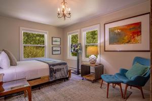 a bedroom with a bed and a chair and windows at Red Elephant | 4BR - Fire Pit - River & Downtown in Hailey