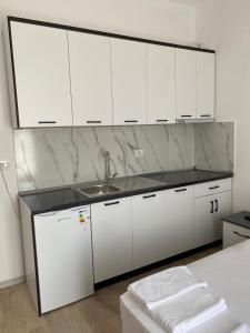 a white kitchen with a sink and white cabinets at Arval Rooms in Vlorë