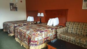 a hotel room with two beds and a couch at Budgetel Inn and Suites in Hearne