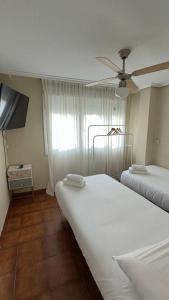 a bedroom with two beds and a ceiling fan at Hostal Entre Puertas in Aranda de Duero