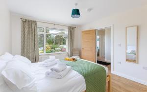 a bedroom with a white bed with towels on it at Westway - 3 Bed Coastal Bungalow with Large Garden Steps from Colwell Bay Beach in Freshwater