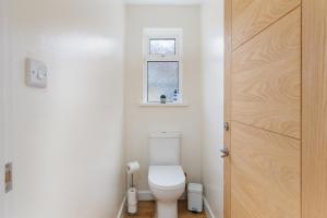 a bathroom with a toilet and a window at Westway - 3 Bed Coastal Bungalow with Large Garden Steps from Colwell Bay Beach in Freshwater +34 photos