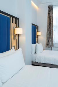 a hotel room with two beds and two windows at Best Western Victoria Palace in London