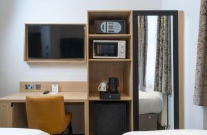 a room with a desk with a microwave and a bed at Best Western Victoria Palace in London