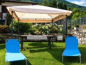 two blue chairs and a table under a tent at Casa Coccinella in Oggebbio