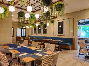 a restaurant with tables and chairs and potted plants at Golden Tulip Essential Belitung in Tanjungpandan