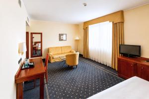 ein Hotelzimmer mit Bett, Schreibtisch und Fernseher in der Unterkunft Phi Hotel Cavalieri in Bra