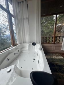a bath tub with a chair in a room with windows at The Swayambhu Hamta in Manāli +20 photos