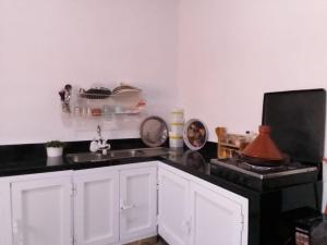 a kitchen with white cabinets and a black counter top at Tigmi Nrayss in Essaouira