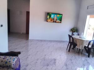 a living room with a table and a tv on a wall at Tigmi Nrayss in Essaouira