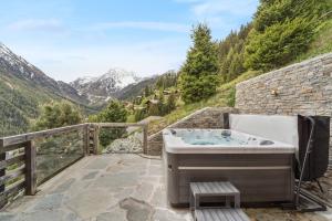 a bath tub on a patio with a view of mountains at Chalet SkyLodge by Mrs Miggins in Grimentz