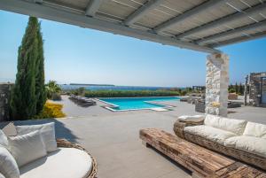 a patio with wicker furniture and a swimming pool at Aelia Paros Beachfront Villas-Member of My Villas Hospitality in Chrissi Akti