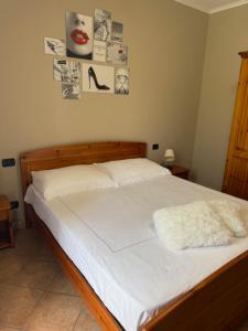 Ein Schlafzimmer mit einem Bett mit weißen Laken und Bildern an der Wand in der Unterkunft Origami in Magliano Alfieri