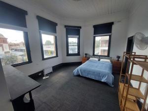 a bedroom with a bed with blue walls and windows at The Vine & Lamb in Saint Arnaud