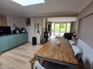 a living room with a wooden table and a kitchen at Marley Farm Bungalow in Deal
