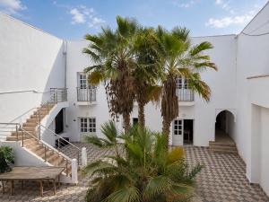 an external view of a white building with palm trees at Hôtel Calipau Riad Maison d'Hôtes in Dakhla
