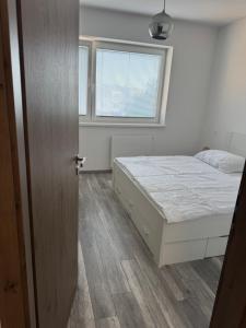 a white bedroom with a bed and a window at Apartman David Topoľčany in Topoľčany +2 photos