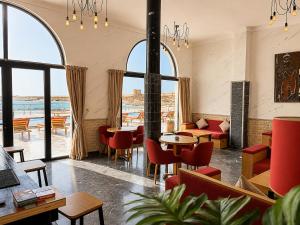 a restaurant with red chairs and tables and windows at Hôtel Calipau Riad Maison d'Hôtes in Dakhla