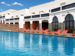 a building with red chairs and a swimming pool at Hôtel Calipau Riad Maison d'Hôtes in Dakhla
