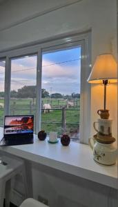 a desk with a laptop on a table with a window at The Stables by L' Rancho Danilo in Banaba +14 photos