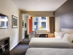a hotel room with two beds and a desk at ibis Wellington in Wellington