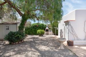 a yard with a tree and a statue next to a building at Casa Susana in Santa Eularia des Riu