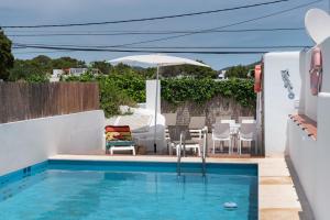 a swimming pool with chairs and an umbrella next to it at Casa Susana in Santa Eularia des Riu