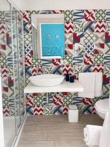 a bathroom with a sink and a mosaic wall at Ciao Ciao Rooms in Letojanni