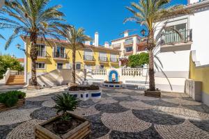 a resort with palm trees and a yellow building at SUNSET Apartment in Amoreira