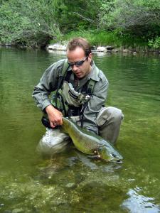a man kneeling in the water with a fish at Hotel Hvala Superior - Topli Val in Kobarid
