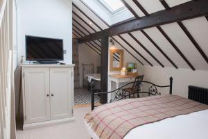 a bedroom with a bed and a television on a cabinet at Tudor Farmhouse Hotel in Clearwell